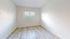 Bright and airy room with fresh white walls and elegant wood flooring, featuring a large window inviting ample natural light.