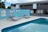Serene apartment pool area with comfortable lounge chairs and a tranquil water view, perfect for relaxation.