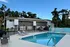 Inviting apartment complex with a pristine swimming pool, lounge chairs, and modern architecture set against lush greenery.