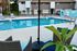 Inviting apartment pool area with comfortable seating, surrounded by modern townhouses, perfect for relaxation and leisure.
