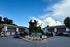 Charming apartment complex with stylish gray exteriors, featuring a landscaped courtyard and inviting pool area under a vibrant blue sky, offering a serene and welcoming environment.