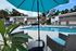 Inviting poolside retreat with chic wicker chairs and a vibrant umbrella, surrounded by modern townhouses and lush greenery.