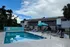 Inviting apartment complex featuring a sparkling outdoor pool, surrounded by elegant lounge chairs and vibrant umbrellas, set against a backdrop of lush greenery.