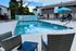 Inviting outdoor pool area with lounge chairs and a vibrant blue umbrella, perfect for relaxation and leisure in a serene community setting.