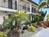 Charming apartment exterior with lush tropical landscaping, featuring vibrant greenery and elegant architectural details.