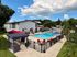 Inviting apartment community with a sparkling swimming pool, lounge chairs, and vibrant umbrellas beneath a clear blue sky.