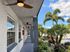 Charming apartment exterior with modern ceilings, lush landscaping, and tall palm trees under a bright blue sky.