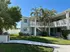 Charming white apartment building with lush greenery and inviting balcony, perfect for enjoying sunny days.