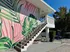 Vibrant apartment exterior with tropical leaf mural, elegant white staircase, and sunny surroundings.