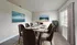 Elegant dining room with contemporary decor, featuring a stylish table set for eight, captivating ocean-themed wall art, and natural light streaming through large windows.