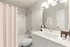 Bright and modern bathroom featuring elegant marble tiles, a stylish vanity with ample storage, and a luxurious bathtub.