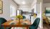 Charming kitchen and dining area with sleek white cabinets, elegant wooden table set with modern dishware, vibrant sunflowers, and cozy seating, perfect for hosting intimate gatherings.