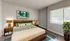 Bright and modern bedroom with stylish decor, featuring a cozy bed, elegant lamps, and vibrant wall art.