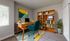 Bright and inviting home office with a wooden desk, teal chair, and stylish bookcase, featuring lush greenery and vibrant artwork.