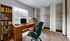 Bright home office featuring a wooden desk with a laptop, stylish green chair, bookshelf filled with books, and spacious closets, ideal for productive work from home days.