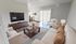 Elegant living room showcasing modern decor, cozy beige sofas, a sleek TV, wooden furniture, and ample natural light from large windows.