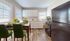 Bright and modern kitchen and dining area featuring elegant white cabinets, a sleek black refrigerator, and vibrant green chairs with a touch of sunflower decor.