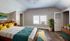 Spacious and inviting bedroom with stylish decor, featuring a cozy bed with vibrant yellow and teal pillows, modern artwork, and lush greenery under natural light.