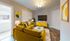 Charming living room with vibrant yellow sofas, modern decor, and a sleek TV setup creating a cozy, stylish ambiance.