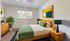 Modern bedroom with sleek wooden furniture, vibrant green accents, and contemporary artwork, creating a serene and inviting ambiance.
