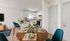 Bright and inviting open-concept kitchen and dining area featuring modern appliances, elegant teal chairs, and a cozy round table set for a delightful dining experience.