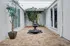 Charming courtyard with a serene stone fountain surrounded by lush greenery and sleek modern design.