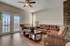 Inviting living room with elegant hardwood floors, plush leather sofa, striped armchairs, and bright natural light from double glass doors.
