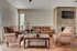 Charming living room with a cozy leather sofa, striped armchairs, and a stone fireplace, perfect for relaxation and entertainment.