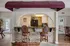 Cozy and elegant kitchen area with stone-faced breakfast bar, leather bar stools, and warm lighting, seamlessly connecting to the dining space.