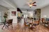 Inviting open-concept living space with elegant wooden flooring, cozy seating by a stone fireplace, and stylish dining area, perfect for entertaining.