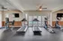 Bright and modern gym featuring top-notch equipment, including treadmills and elliptical machines, overlooking a serene outdoor pool.