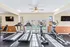 Bright and modern fitness center featuring treadmills and elliptical machines with a view of the outdoor pool through large windows.