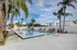 Inviting outdoor pool area with clear blue waters, surrounded by lush palm trees and modern lounge chairs, perfect for relaxation.