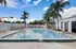 Inviting outdoor pool area with palm trees, comfortable lounge chairs, and a vibrant blue sky backdrop.