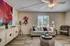 Charming living room with modern decor, featuring vibrant art, cozy sofa, and natural light from a large window.