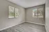 Bright and airy room with modern gray flooring and large windows offering a pleasant outdoor view.