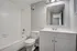 Modern bathroom with sleek white fixtures, featuring a spacious bathtub, elegant vanity, and large mirror, offering a bright and inviting atmosphere.