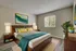 Inviting bedroom with modern decor featuring a wooden bed, colorful bedding, and large window providing natural light.