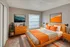 Contemporary bedroom with stylish orange accents, featuring modern wooden furniture and vibrant artwork, perfect for a cozy and chic living space.