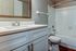 Contemporary bathroom with a sleek white vanity, elegant mirror, and tile bathtub, offering a clean and modern aesthetic.