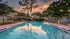 Inviting residential pool area with lounge chairs and lush greenery, set against a stunning sunset sky.