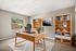 Bright and sophisticated home office with stylish desk, bookshelves filled with books and decor, a large window allowing natural light, and elegant artwork on the wall.
