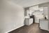 Contemporary kitchen with sleek white cabinets, modern appliances, and elegant countertop, set against stylish wood flooring.