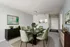 Elegant dining room with a modern green theme, featuring a stylish dark wood table, matching chairs, minimalist decor, and contemporary artwork.
