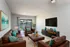 Inviting living room with elegant leather sofas, vibrant turquoise accents, and a sleek wall-mounted TV, perfect for relaxation and entertainment.