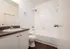Modern bathroom with sleek white tiles, elegant vanity, and a clean bathtub, perfect for relaxation and rejuvenation.
