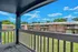 Charming apartment balcony view showcasing lovely brick buildings, lush green lawns, and a bright blue sky.