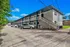 Charming two-story apartment complex with blue accents, ample parking, and a welcoming outdoor staircase under a clear blue sky.