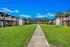 Charming apartment complex with spacious greenery and welcoming balconies, surrounded by serene trees and a bright blue sky.