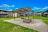 Charming apartment complex courtyard with a rustic wooden pergola, lush green lawns, and cozy balconies overlooking the space.